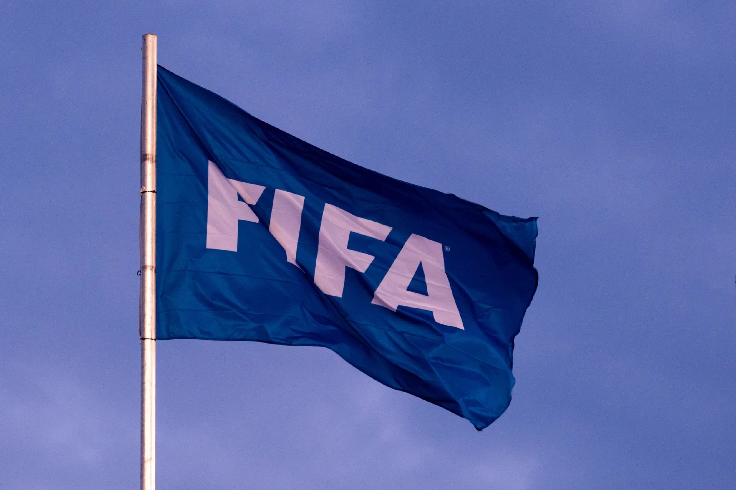 Bandeira azul da FIFA hasteada ao céu, representando notícia sobre transfer ban Corinthians no mercado da bola.